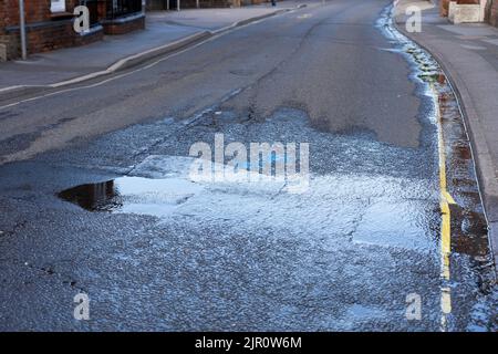 À la fin de la sécheresse de 2022, un tuyau d'eau qui éclate sur la route Winchester provoque un déversement d'eau sur la route et une perte dans le drain. Basingstoke. ROYAUME-UNI Banque D'Images