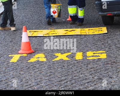 Les travailleurs de la route peignent le mot taxis dans la rue Banque D'Images