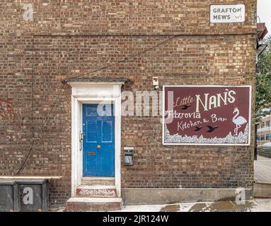 A blue door and door step with a sign for Little Nan's Kitchen & Bar on the side of a brick building wall on Grafton Mews, Fitzrovia, London W1 Banque D'Images