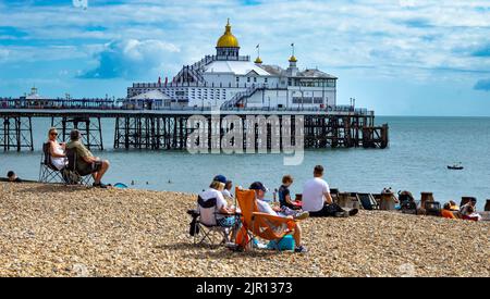 Les gens s'assoient sur la plage à côté de Eastbourne Pier, ESAT Sussex, Royaume-Uni. Banque D'Images