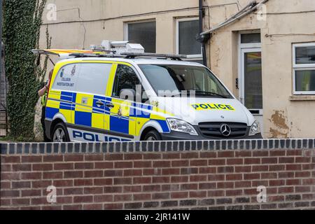 Une fourgonnette de l'unité d'enquête de collision de la police de Wiltshire garée dans un petit parking à côté d'un bâtiment avec un agent travaillant à l'arrière avec le boo Banque D'Images