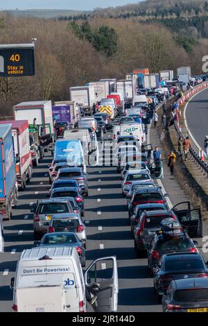 3 voies de circulation en file d'attente sur une autoroute britannique avec des conducteurs hors de leur voiture lorsqu'un embouteillage se forme en raison de la fermeture de l'autoroute en raison d'une emerenc Banque D'Images