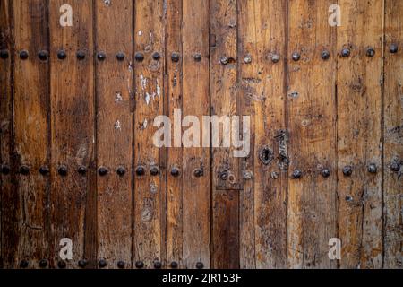 Porte antique à double battant avec des perches en métal et des décorations sur bois naturel sombre Banque D'Images