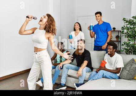 Groupe de jeunes amis ayant la fête chantant la chanson en utilisant le microphone à la maison. Banque D'Images