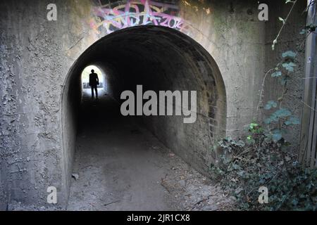 Lumière au bout du tunnel. Un chiffre marchant dans un tunnel sous le chemin de fer à Wolverton. Banque D'Images