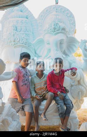 Pileru, Inde - 28 juillet,2022:trois enfants indiens de la rue posant devant le seigneur ganesha. Banque D'Images