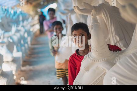 Pileru, Inde - 28 juillet,2022: Les enfants posant à côté de ganesha idoles.taureau sculpture dans la peau de front.brown enfant avec chemise rouge à l'avant. Banque D'Images