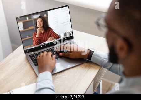 Black Man utilisant un ordinateur portable pour des cours d'anglais en ligne avec un tuteur féminin Banque D'Images