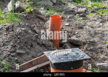 Inspection du système d'égout à l'aide d'un trou d'homme fermé en fonte, de tuyaux en plastique visibles. Banque D'Images
