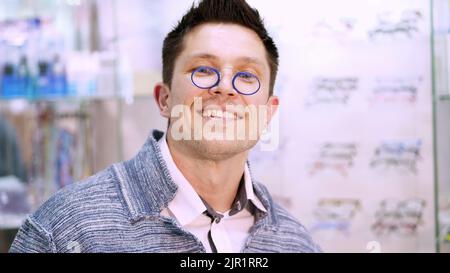 L'homme prend une paire de lunettes de pince-nez dans un petit étui, essaie sur eux. Portrait d'un jeune homme beau qui choisit des lunettes dans un magasin d'opticien. Concept de soins de santé. Photo de haute qualité Banque D'Images