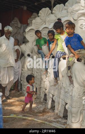 Pileru, Inde - 28 juillet,2022:fille offrant main à bébé de haut en haut. Photo de rue avec les enfants et les idoles de ganesha. Les enfants étaient assis sur les idoles de ganesha. Banque D'Images