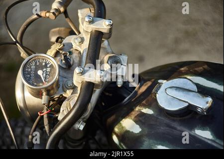 Détail du guidon et du compteur de vitesse d'une moto noire vintage, avec détails de contrôle et chrome visibles. Banque D'Images