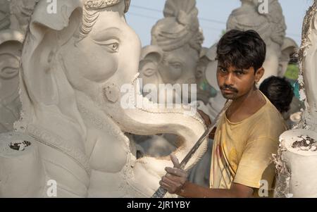 Pileru, Inde - 28 juillet,2022: Jeune artiste regardant la caméra avec couteau dans la main.ganesha idoles sont en préparation. Banque D'Images