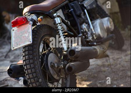 Durée de vie d'une partie arrière d'une moto vintage avec des tuyaux d'échappement clairement visibles, la roue et les nombreuses pièces mécaniques dont elle est faite. Banque D'Images