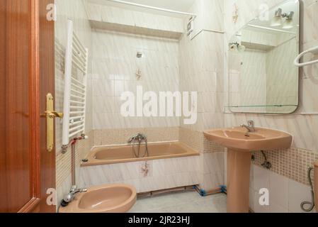 Salle de bains avec lavabo sur pied en porcelaine brune, miroir sans cadre assorti, carreaux blancs et bruns avec bordure Banque D'Images