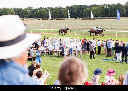 Langenhagen, Allemagne. 21st août 2022. Les visiteurs de l'Audi Ascot Renntag s'assoient sur la pelouse en face de l'hippodrome et regardent une course à cheval. L'Audi Ascot Renntag à l'hippodrome de Neue Bult se déroule à nouveau cette année pour la première fois en deux ans. La raison en était la pandémie de Corona. Credit: Michael Matthey/dpa/Alay Live News Banque D'Images