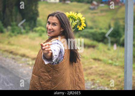 Une jeune femme marche dans les montagnes avec un bouquet de tournesols. Banque D'Images