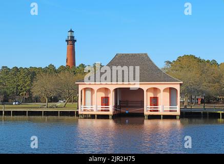 La structure en brique rouge du phare de Currituck Beach s'élève au-dessus d'une serre à bateaux rose dans un parc historique près de Corolla, en Caroline du Nord Banque D'Images