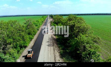 Vue aérienne sur la nouvelle route asphaltée, réparation de la route. Il y a de l'asphalte posé d'un côté de la circulation. En raison de la réparation, le mouvement inverse fonctionne d'un côté de la route,. Photo de haute qualité Banque D'Images