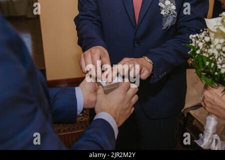 Un gros plan d'un homme prenant un anneau de mariage de la boîte tandis qu'un autre homme la tenant Banque D'Images