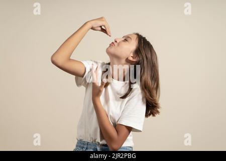 Photo d'une adorable jeune femme montrant des doigts délicieux dessert rêveur isolé sur fond beige. Banque D'Images