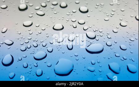 Gouttes de pluie sur une surface en verre lisse, vue à faible angle avec une faible profondeur de champ. Banque D'Images