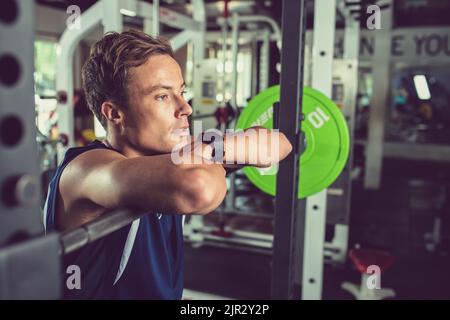 Beau jeune homme sportif ayant une courte pause après avoir levé le poids Banque D'Images