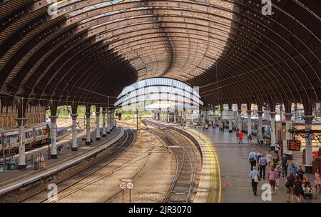 Vue panoramique sur une gare couverte par une voûte du 19th siècle. Les trains attendent sur les quais et les passagers se rendent aux trains. Banque D'Images