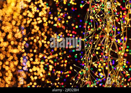 Lumières de Noël sur guirlandes électriques, mise au point sélective. Décorations colorées du nouvel an, éclairage festif en ville Banque D'Images