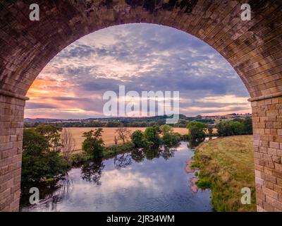 Météo au Royaume-Uni : vue magnifique sur le coucher de soleil au-dessus de la campagne du Yorkshire et de la rivière Wharfe vue à travers une arche du Viaduc d'Arthington. Banque D'Images