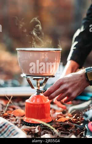 Homme préparant de la soupe à la main sur un poêle à gaz portable Banque D'Images