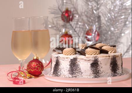 Gâteau de Noël et deux verres de vin blanc sur une table de Noël contre un arbre de Noël argenté décoré Banque D'Images