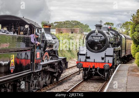 BR 'Manor' 4-6-0 No. 7822 'Foxcote Manor' attend que BR 4MT 4-6-0 No. 75069 arrive à la station Blue Anchor sur le chemin de fer West Somerset, Somerset Banque D'Images