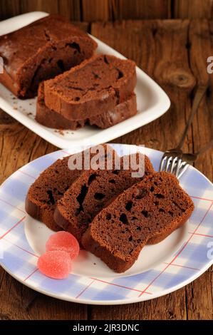 Gâteau au chocolat fait maison coupé avec des bonbons roses sur fond de bois vertical Banque D'Images