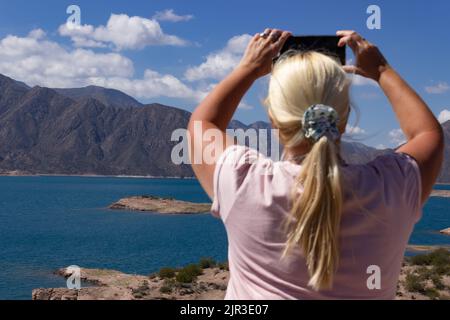 Femme blonde prenant une photo dans un beau paysage. Banque D'Images
