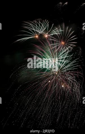 Feux d'artifice rouges et blancs dans le ciel nocturne. Banque D'Images