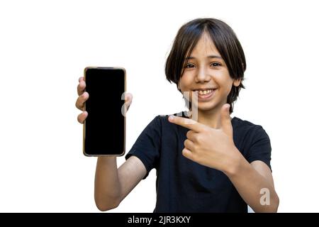 Un jeune garçon asiatique souriant tient un smartphone dans sa main et montre son doigt sur un écran vierge. Joyeux garçon brunette pointant vers le téléphone Banque D'Images