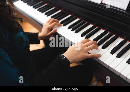 Gros plan sur les mains de la femme jouant du piano en lisant de la musique en feuilles. Mise au point sélective Banque D'Images