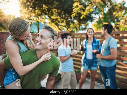 Parfois, les meilleures relations commencent comme des amitiés. Un jeune couple qui profite d'une promenade en pigeyback tout en traînant avec leurs amis. Banque D'Images