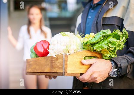 Vous apporter l'épicerie. Un coursier faisant une livraison d'épicerie à un client. Banque D'Images