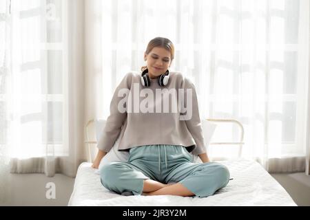 Bonne jeune femme portant des écouteurs écouter de la musique tout en dansant et chantant avec plaisir et de profiter dans le salon, la femme de bonheur avec le divertissement Banque D'Images