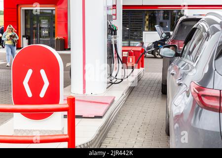 Femme avec chien à la station-service acheté essence va à la voiture, les voitures noires attendant pour le ravitaillement en carburant réservoir. L'homme a son voiture au magasin Lukoil Kemerovo, Banque D'Images