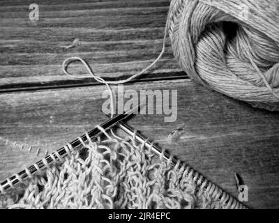 Nappe ajourée dans le processus de tricotage. Aiguilles à tricoter, boucles sur aiguilles à tricoter, tissu tricoté, pelote de fil, coton grossier et lin Banque D'Images