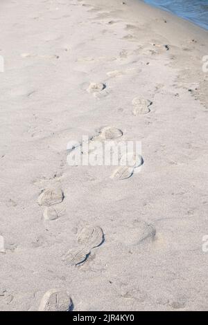 Empreintes de bottes de randonnée sur le sable d'une plage éloignée Banque D'Images