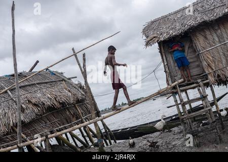 Un garçon a vu traverser un pont en bambou pour aller dans sa maison au village de Kalabogi à Khulna. Il n'y a pas si longtemps, Kalabogi, un village côtier du Bangladesh, était plein de terres cultivables jusqu'à ce que l'élévation du niveau de la mer commence à avaler la région jusqu'à la baie du Bengale. Des cyclones et des inondations fréquents ont frappé le village depuis la fin de 1990s. En 2009, un important cyclone nommé Aila a détruit les 1 400 kilomètres de remblais, 8 800 kilomètres de routes et environ 3,50,000 acres de terres agricoles du pays. Plusieurs centaines de personnes auraient été tuées dans la catastrophe. Les agriculteurs de Kalabogi ont été les plus touchés. A Banque D'Images