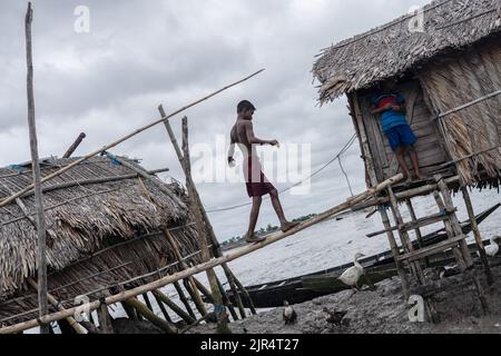 Un garçon a vu traverser un pont en bambou pour aller dans sa maison au village de Kalabogi à Khulna. Il n'y a pas si longtemps, Kalabogi, un village côtier du Bangladesh, était plein de terres cultivables jusqu'à ce que l'élévation du niveau de la mer commence à avaler la région jusqu'à la baie du Bengale. Des cyclones et des inondations fréquents ont frappé le village depuis la fin de 1990s. En 2009, un important cyclone appelé Aila a détruit les 1 400 kilomètres de remblais, 8 800 kilomètres de routes et environ 3 50 000 acres de terres agricoles du pays. Plusieurs centaines de personnes auraient été tuées dans la catastrophe. Les agriculteurs de Kalabogi ont été les plus touchés. Banque D'Images