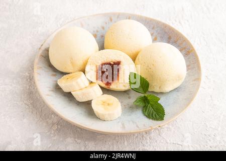 Riz japonais doux petits pains mochi rempli de confiture sur un fond en béton gris. Vue latérale, gros plan. Banque D'Images