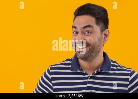 Portrait d'un jeune homme souriant avec des sourcils relevés sur fond jaune Banque D'Images