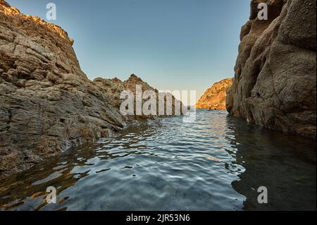 Vue depuis l'eau d'une paire de falaises typiques de la côte sud de la Sardaigne. Banque D'Images