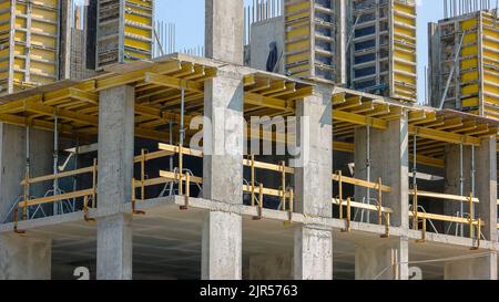 Construction non finisée de gratte-ciel de bâtiment avec cadre en métal. Fond bleu ciel. Banque D'Images